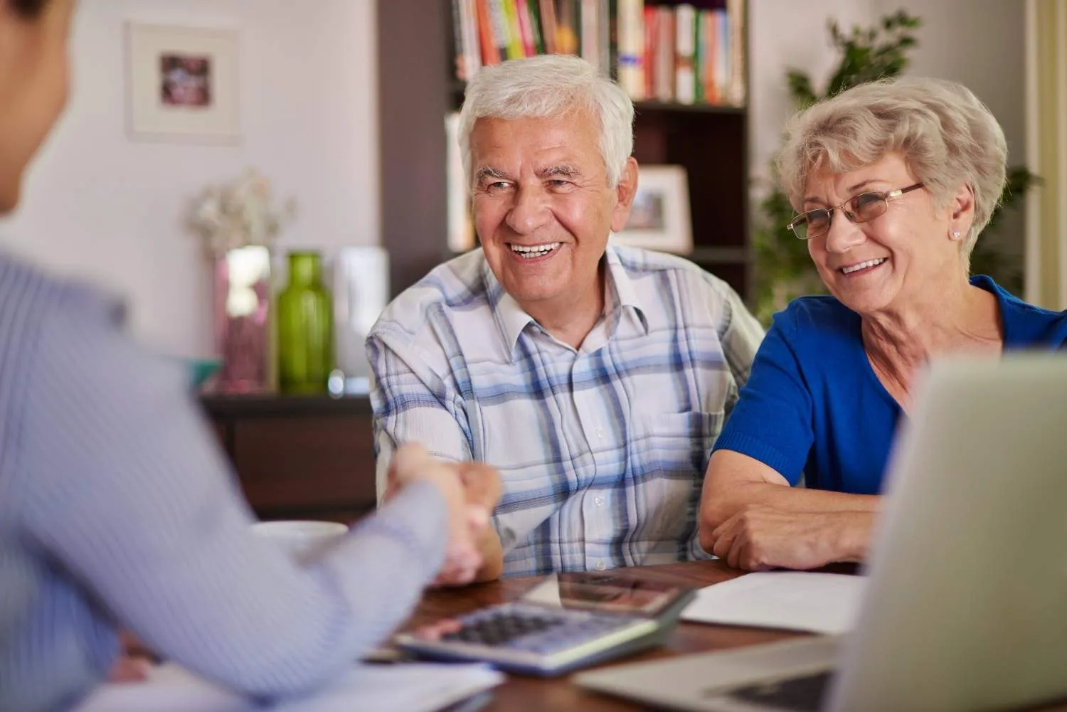 Smiling older couple shaking hands over their coverage papers