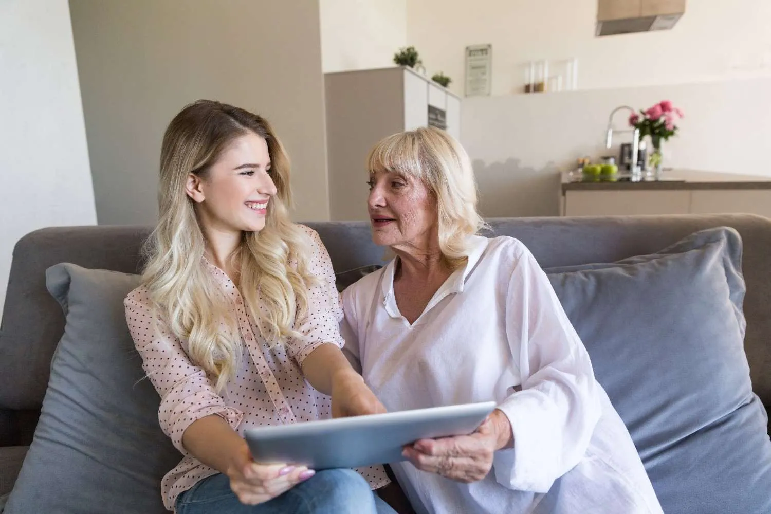 Older mother and adult daughter looking at a tablet together